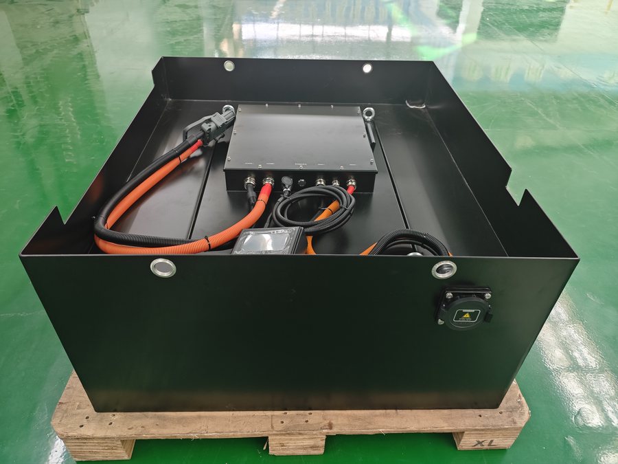 Black LiFePO4 traction pack with its cable loop and connectors laid on the lid